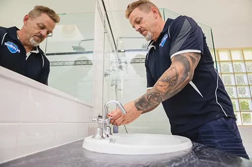 Plumbers fitting a basin tap