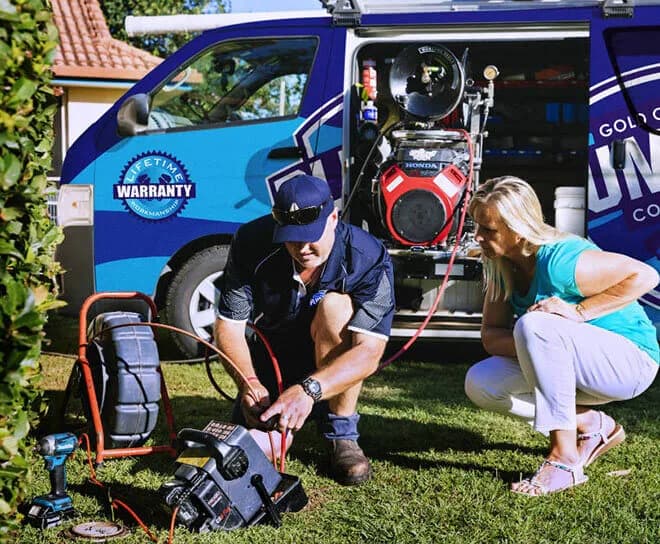 Plumber running a drain camera beside the van